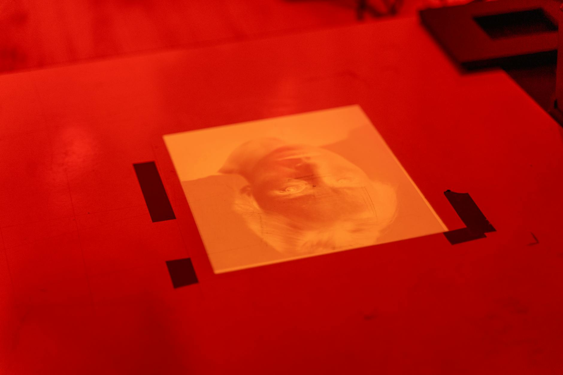 An illuminated orange image of a person's face projected onto a red surface.